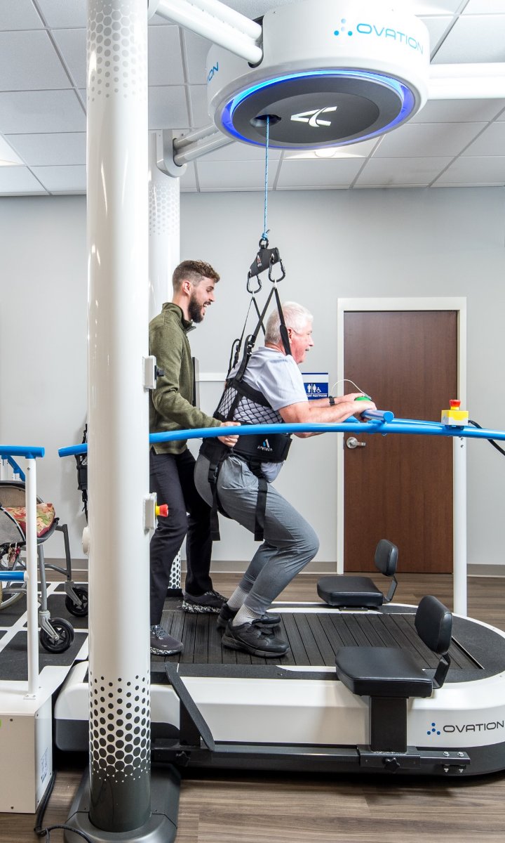Patient supported by the Ovation harness with a therapist assisting on the treadmill