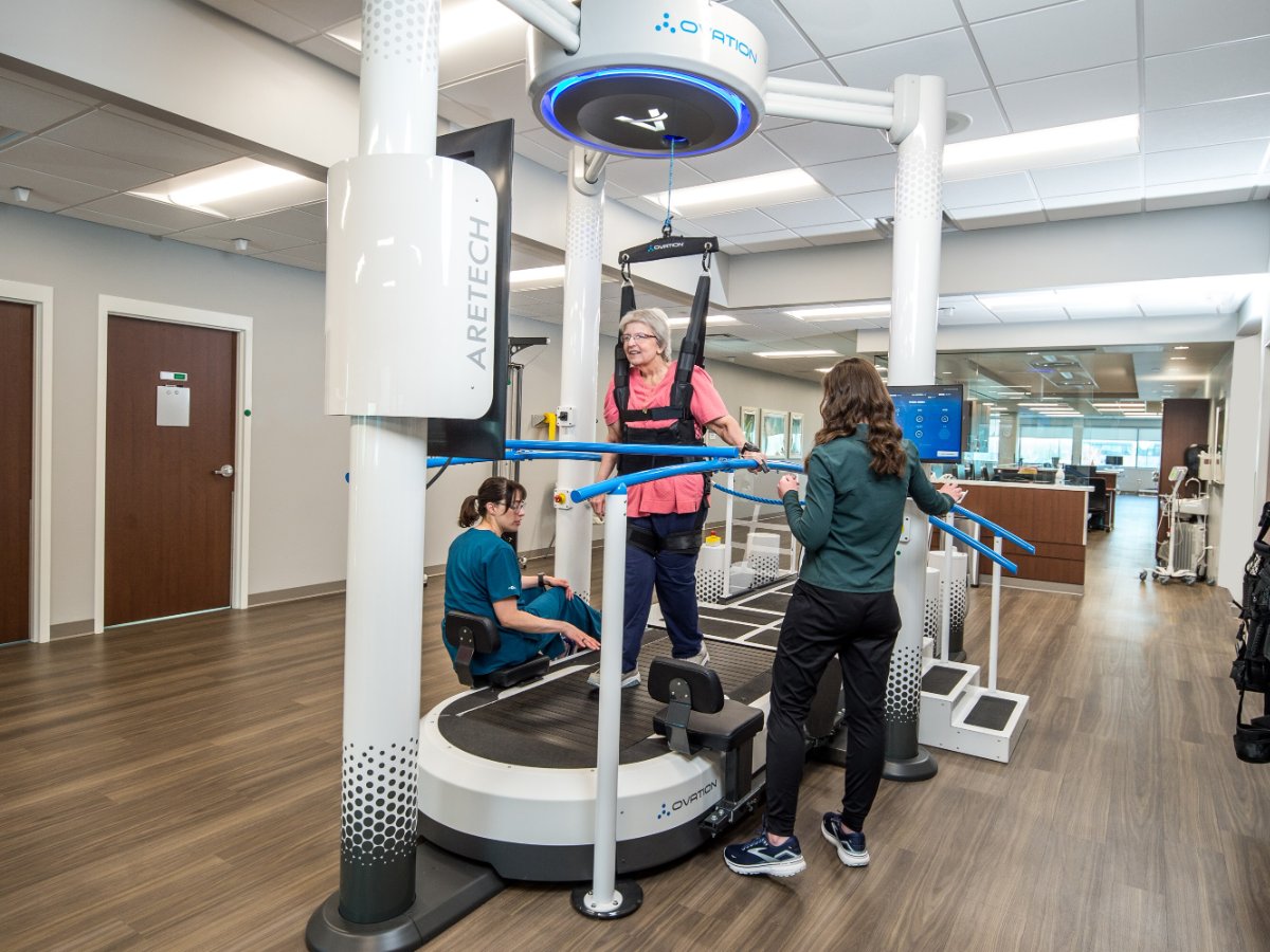 Patient walking on the Ovation system with two therapists assisting