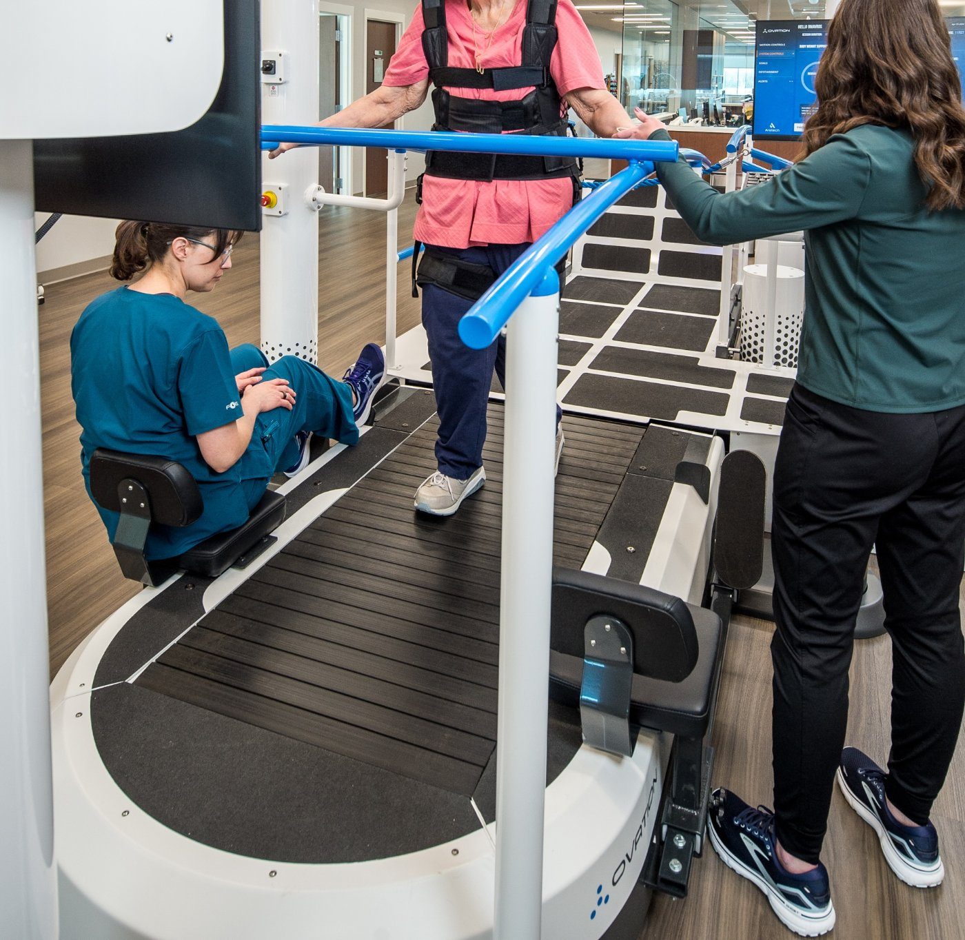 Close view of the Ovation slat-belt treadmill surface with therapists assisting a patient