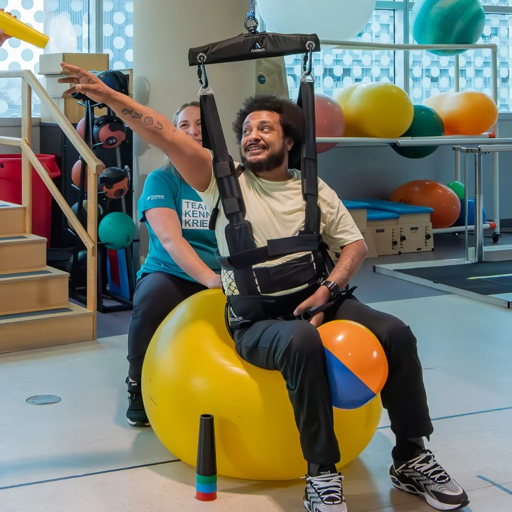 Patient on a therapy ball supported by ZeroG fall protection